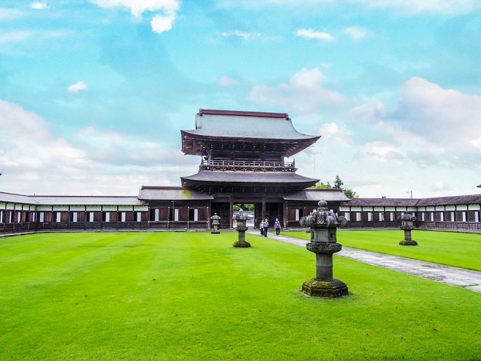 Bâtiment japonais traditionnel entouré d'une pelouse verte et de lanternes en pierre