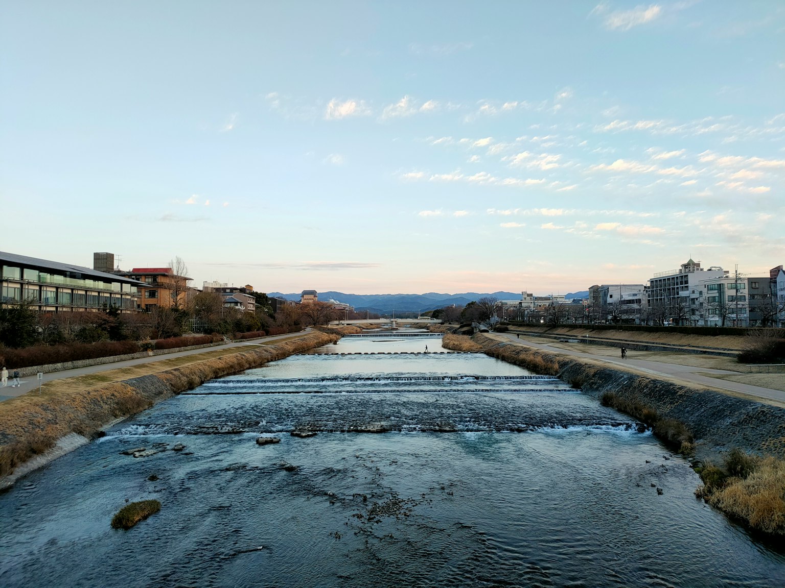 Paisaje de río sereno con edificios bajo un cielo azul