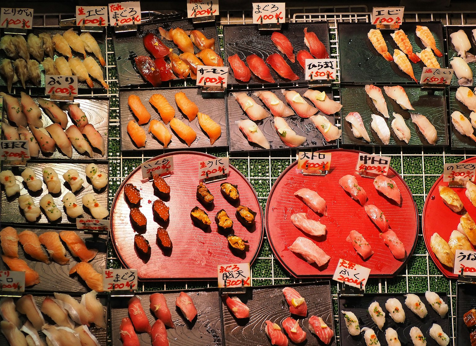 Màn trình bày sushi đầy màu sắc với nhiều loại được sắp xếp trên đĩa và nhãn rõ ràng