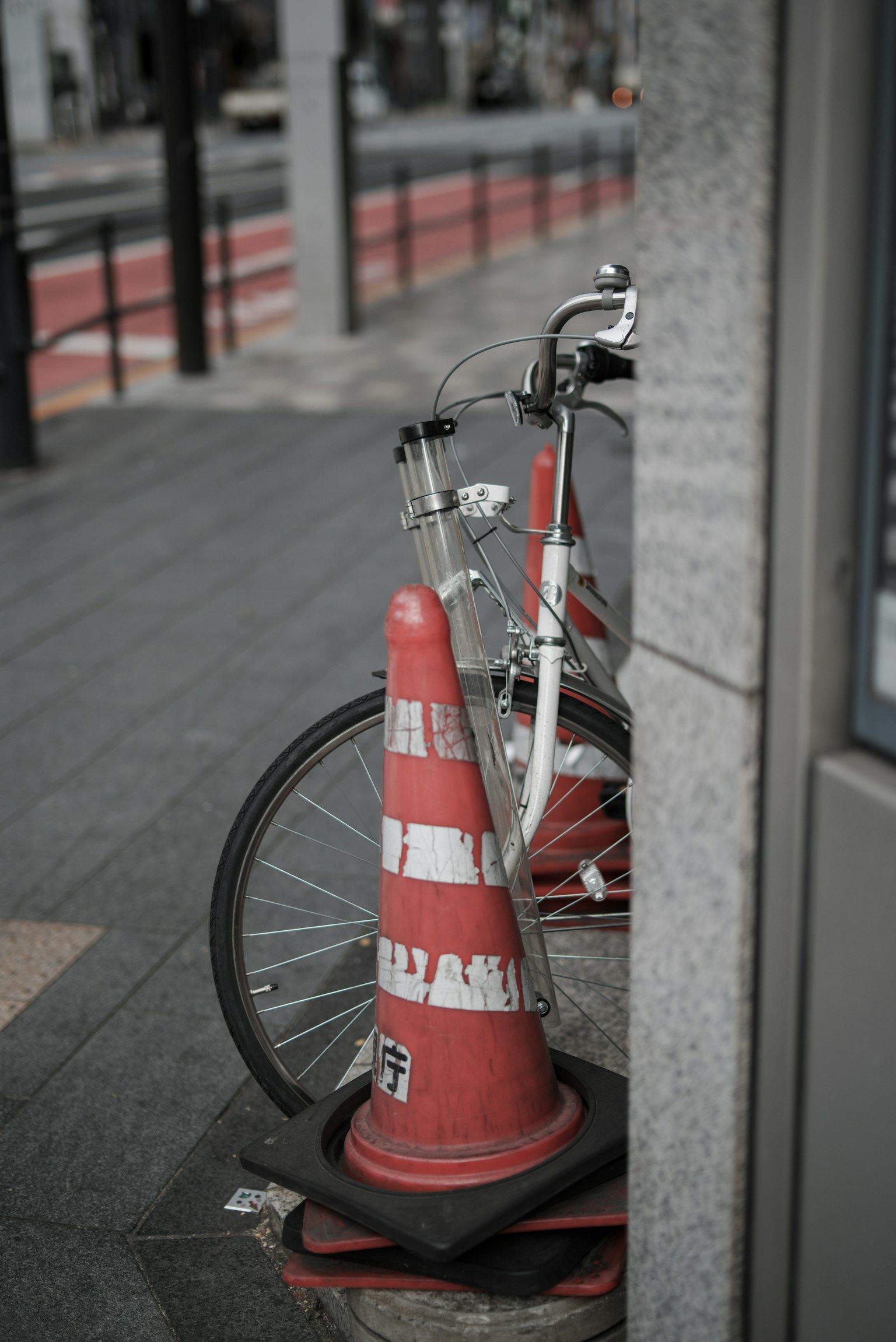 一輛白色自行車靠在城市人行道上的紅色交通錐上