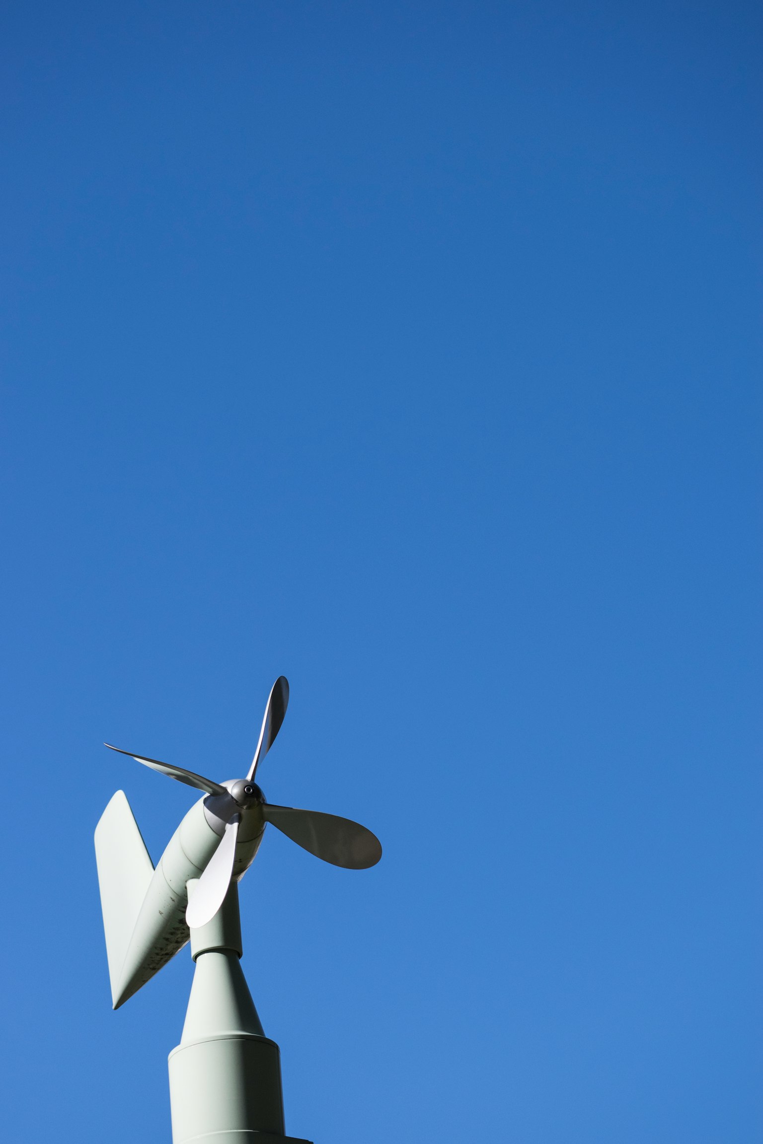 Pales d'une petite éolienne contre un ciel bleu clair