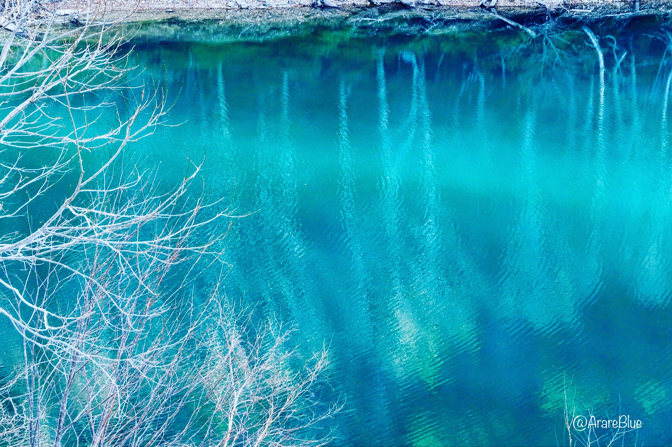 blue waterfall spilling into a turquoise river with mist