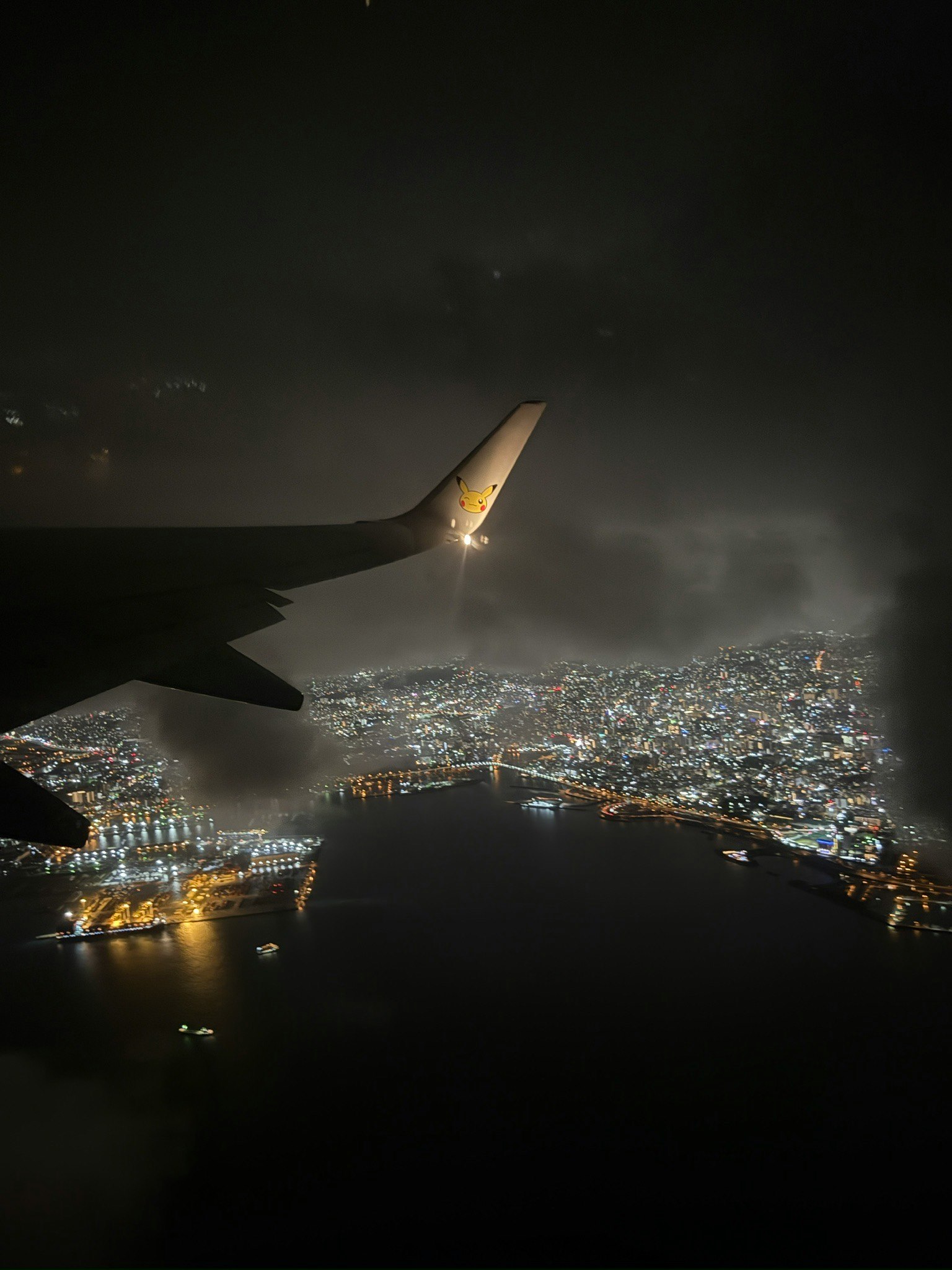 Aerial view of a city illuminated at night seen from an airplane window with bright city lights
