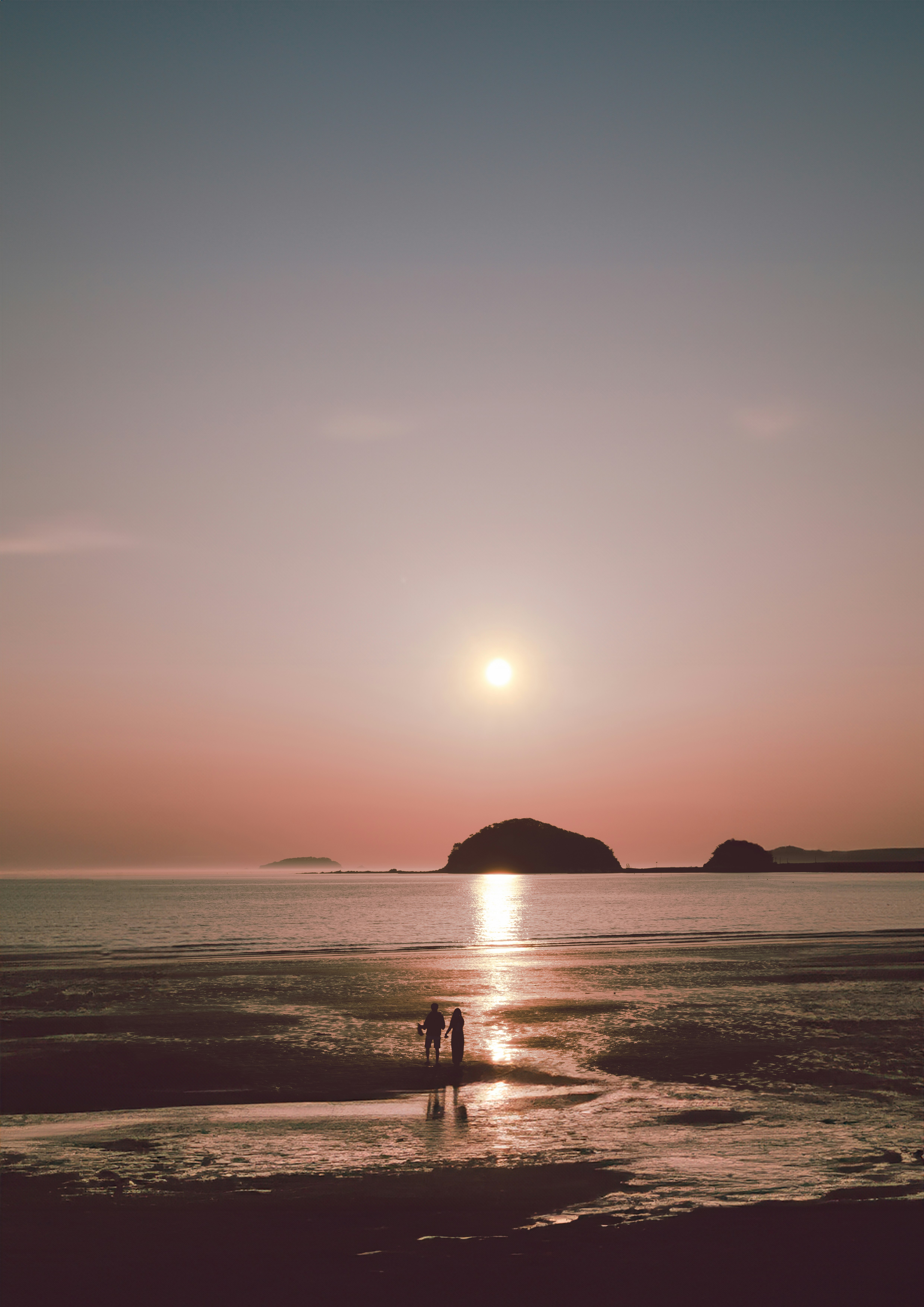 夕日に照らされた海辺の砂浜と小さな島影