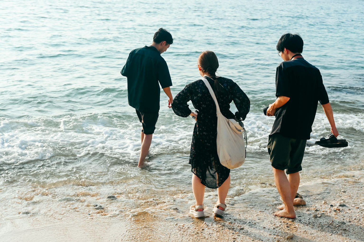 三位年輕人在海灘踩水