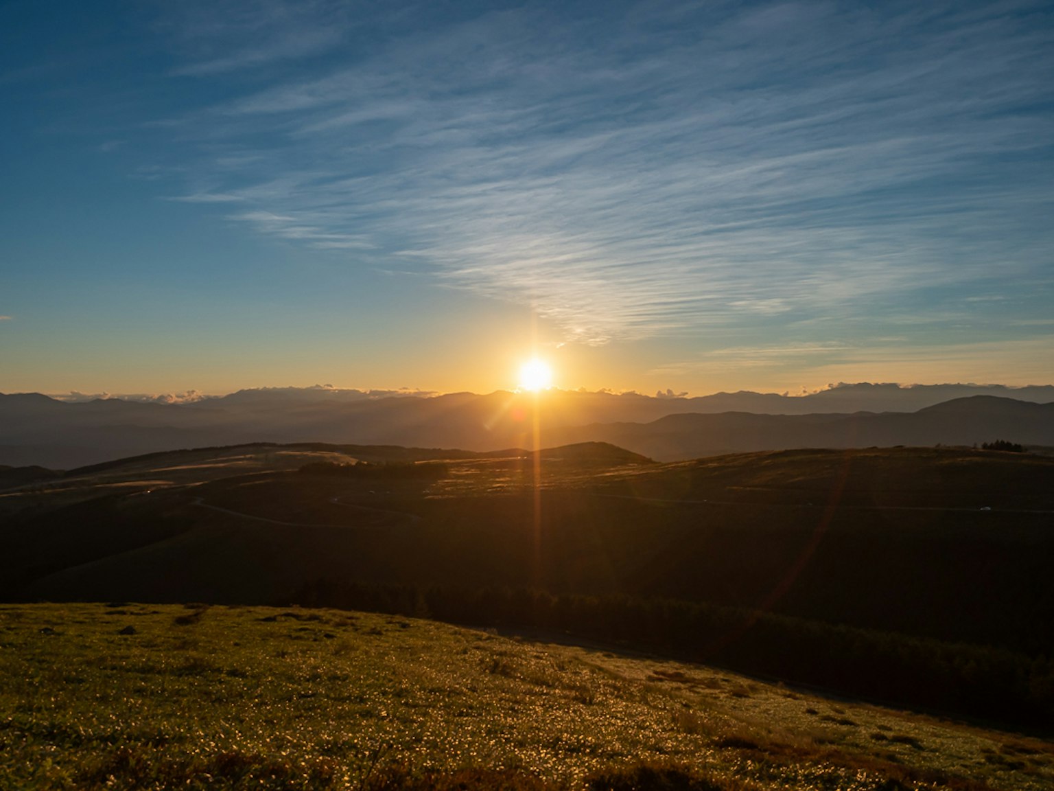 Beautiful sunrise over green hills and mountains