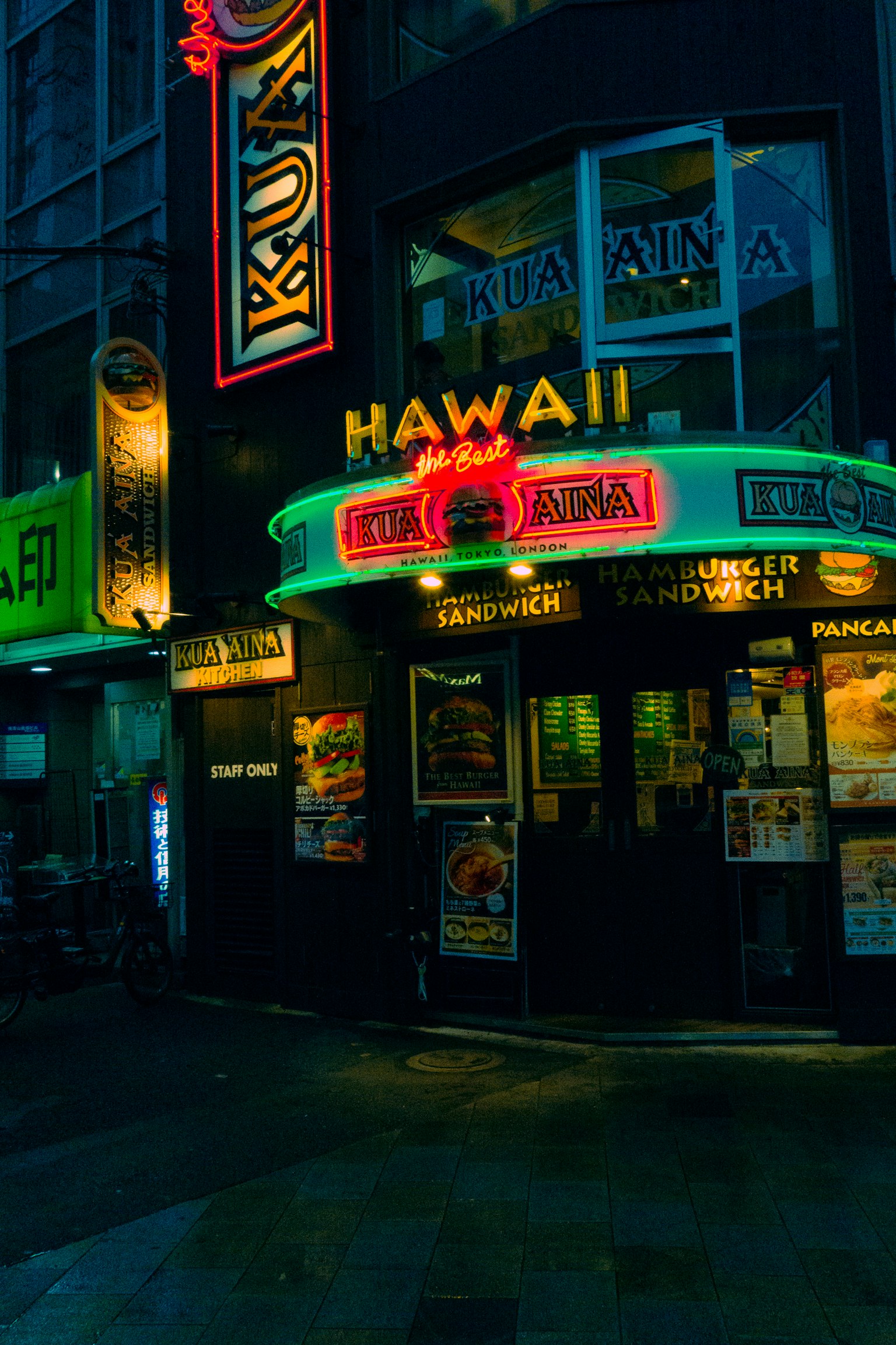 Bên ngoài nhà hàng Hawaii với đèn neon rực rỡ trong bối cảnh đô thị ban đêm