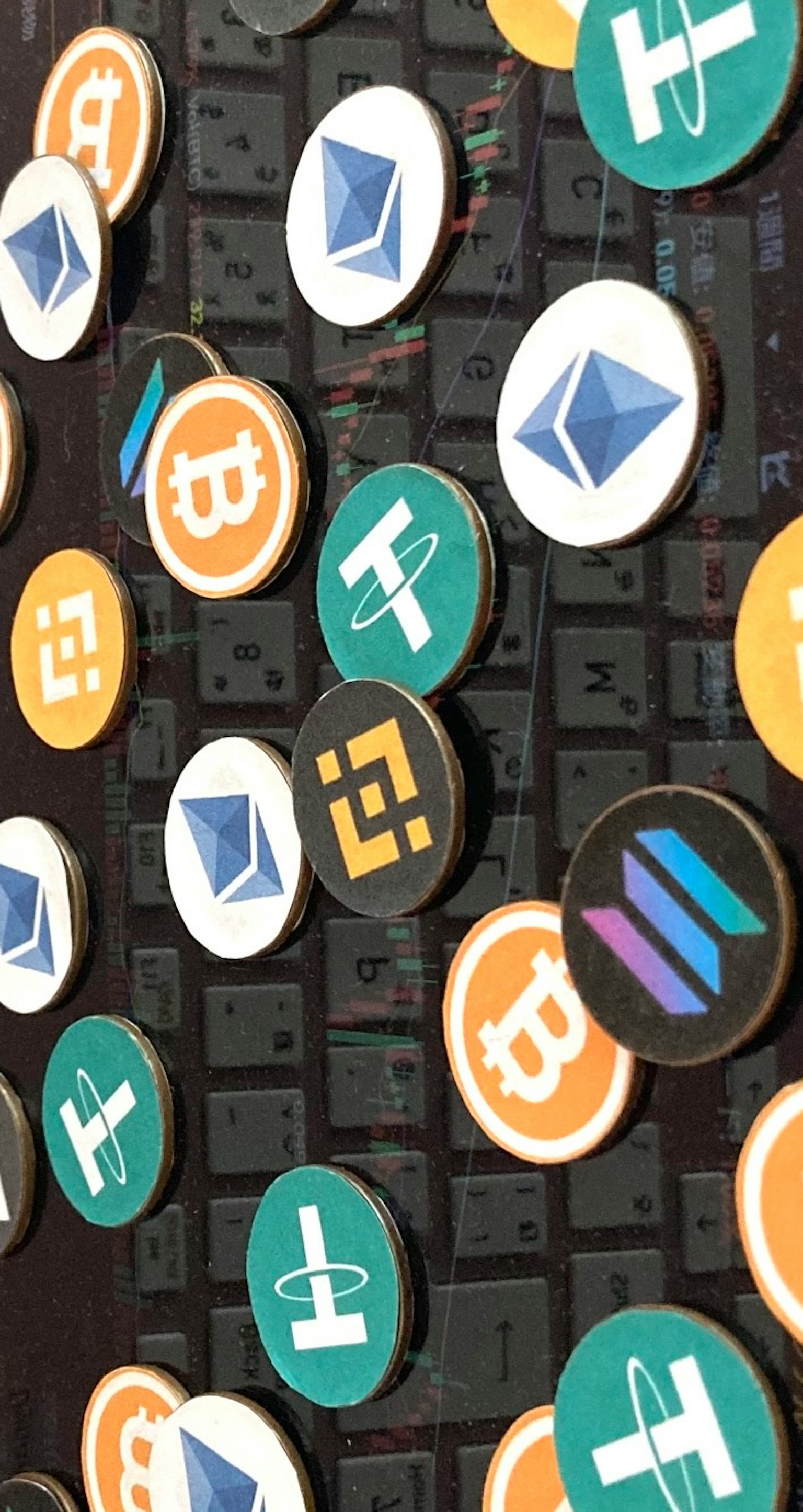 Des pièces de cryptomonnaie colorées disposées sur un clavier noir