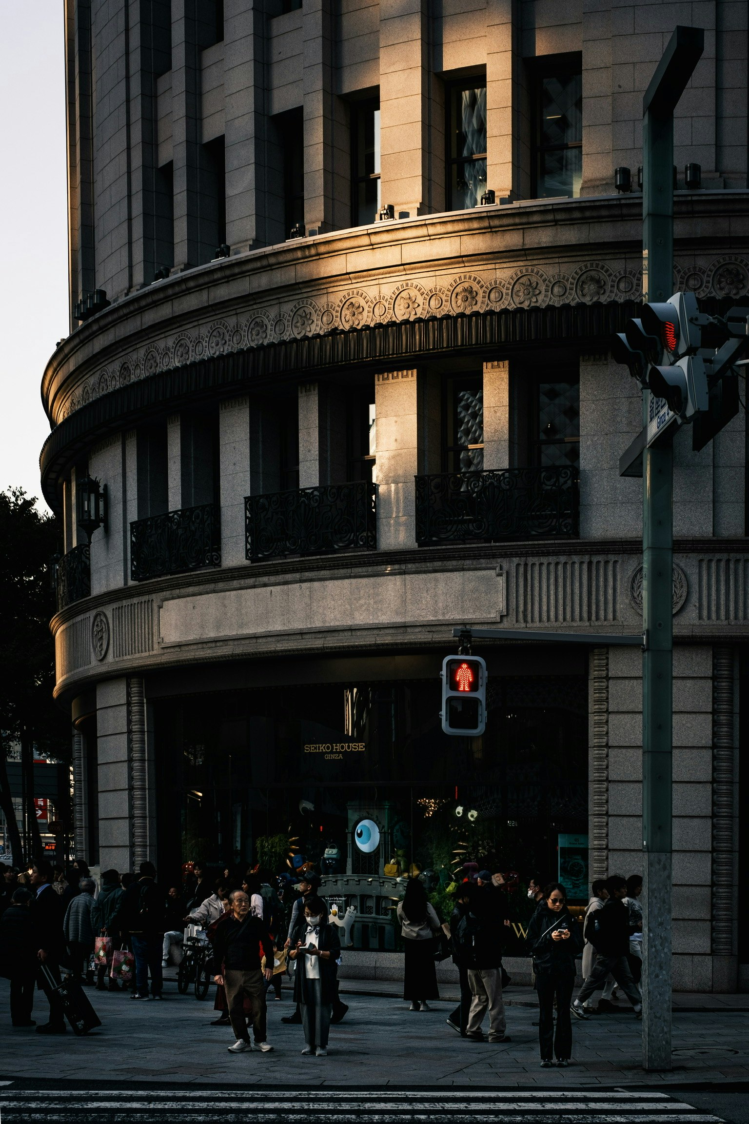 Menschenmenge an einer Straßenecke mit reflektierendem Sonnenlicht