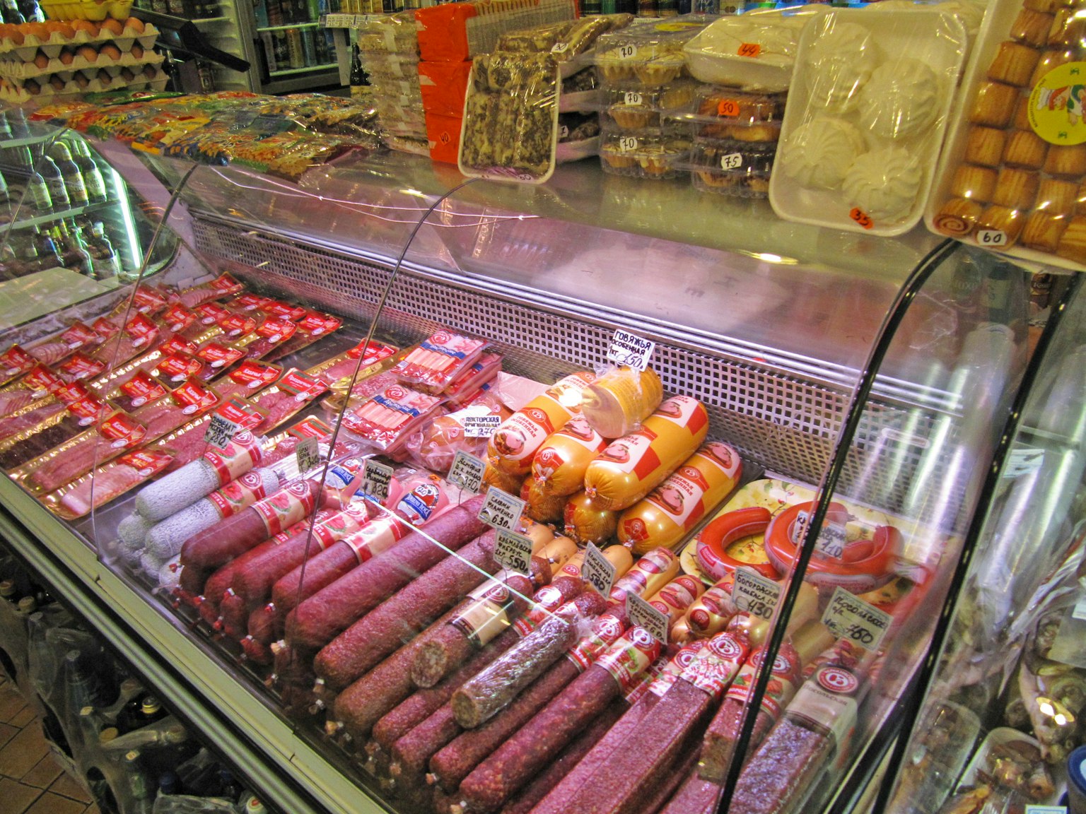 Vetrina piena di vari tipi di carne tra cui salsicce e prosciutti colorati