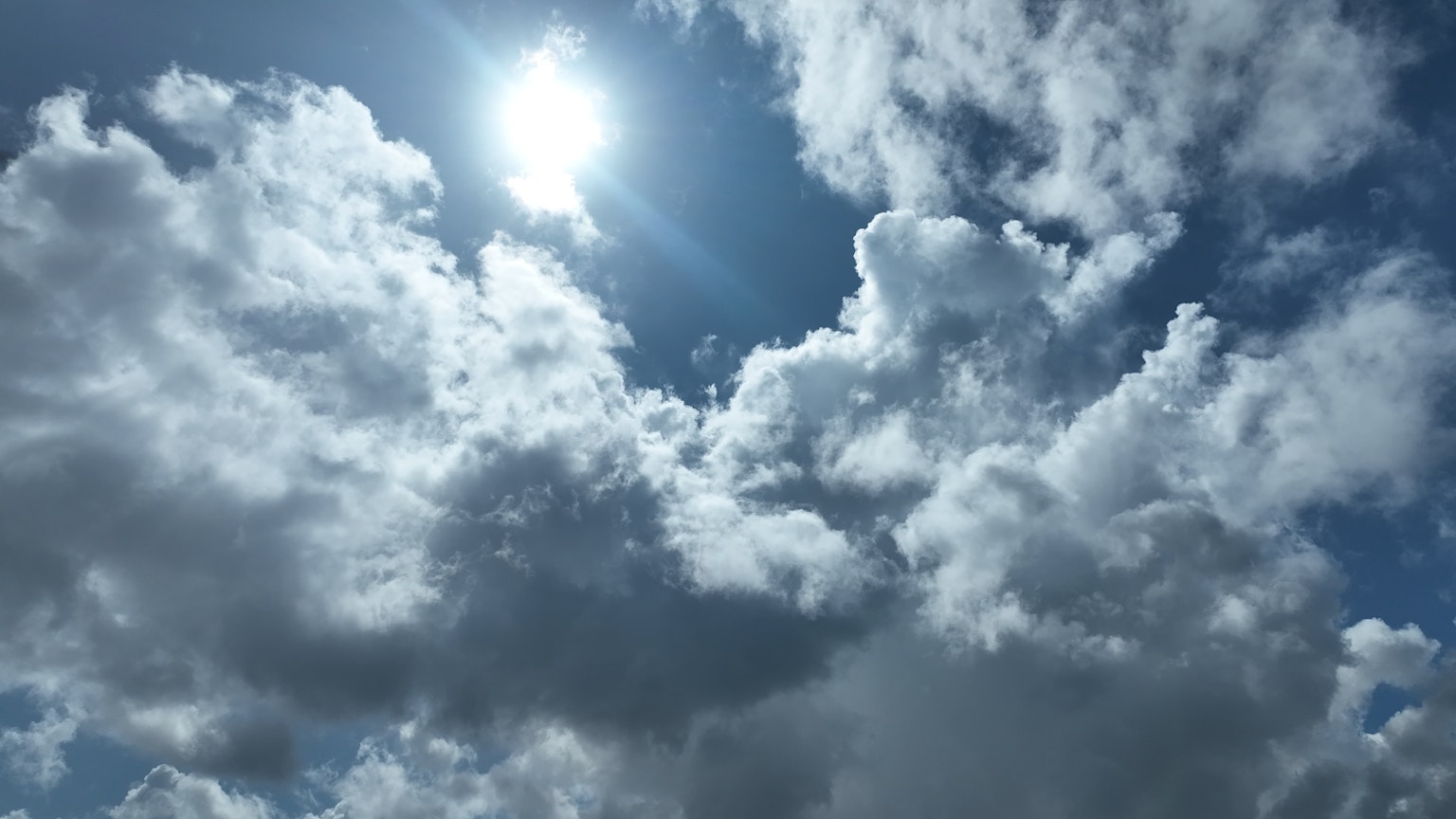 White clouds against a blue sky with bright sunlight