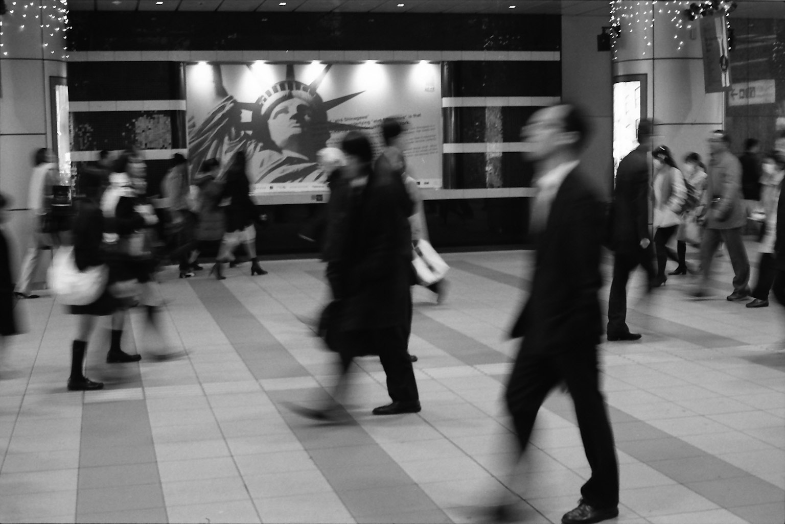 Escena urbana en blanco y negro con personas caminando apresuradamente