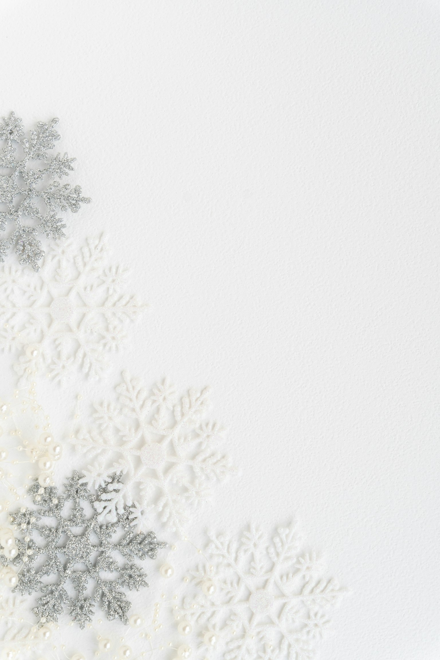Diseño simple y hermoso con copos de nieve plateados esparcidos sobre un fondo blanco