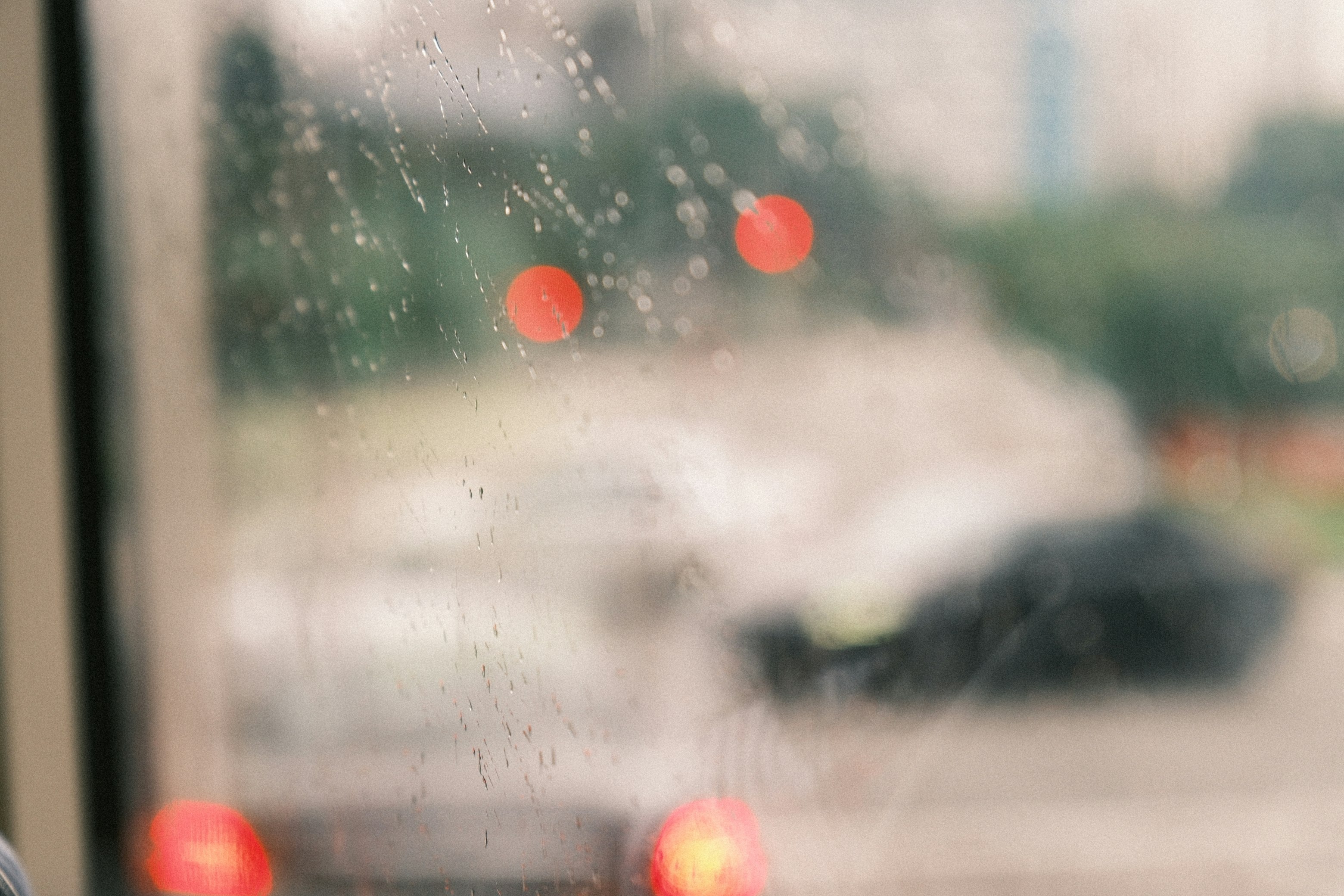 雨粒のついた窓越しにぼけた街並み