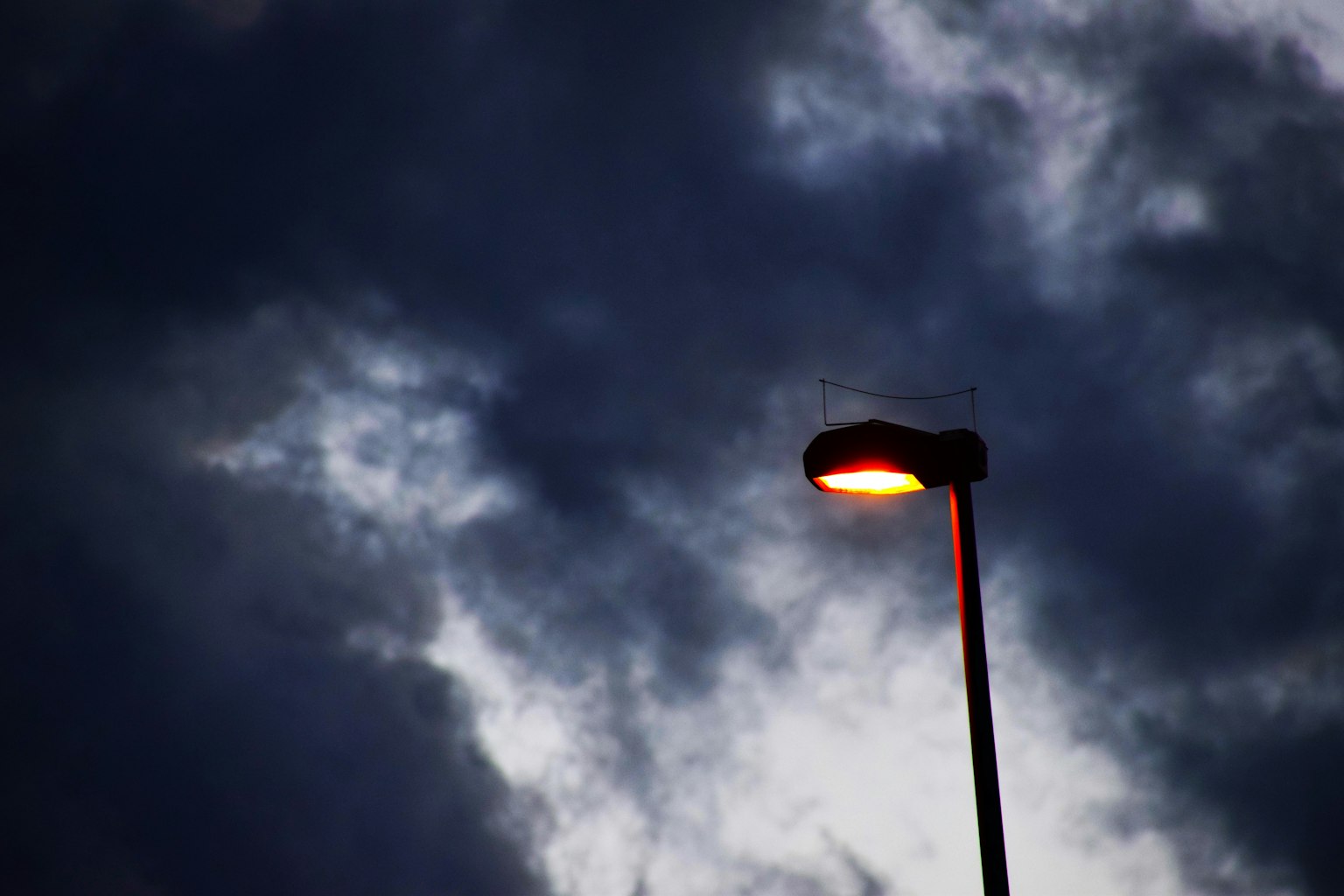 Lampu jalan bersinar di langit mendung gelap