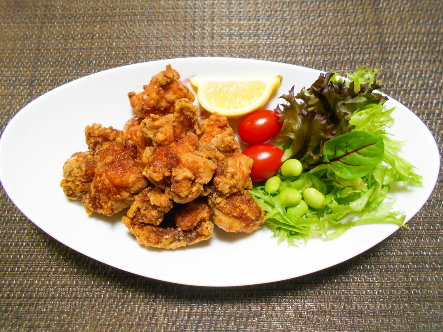 Plato de pollo frito con verduras y una rodaja de limón