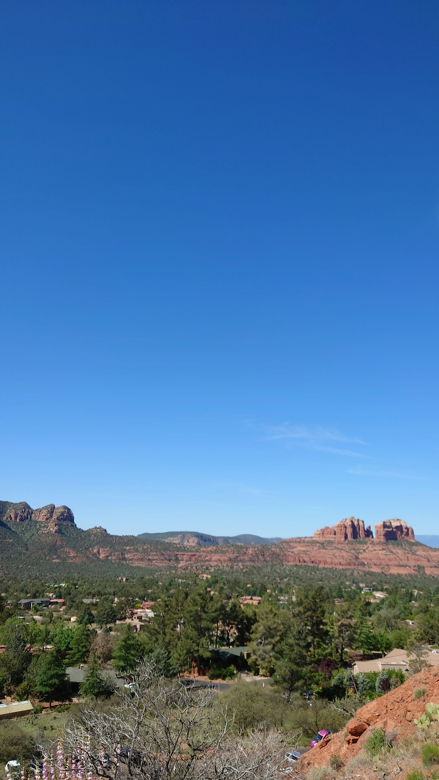 Paisaje con cielo azul y formaciones rocosas rojas árboles verdes y colinas onduladas