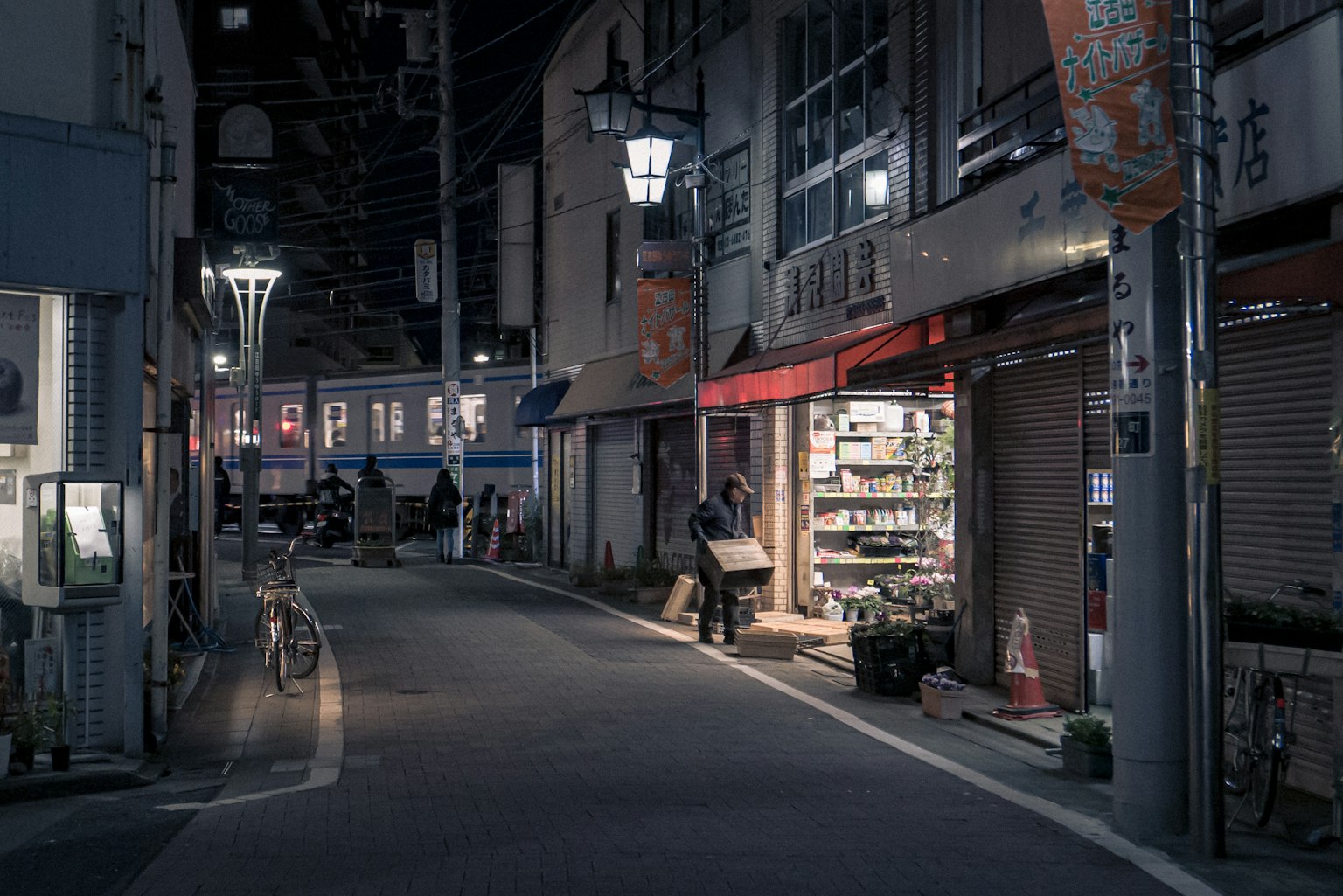 ถนนแคบที่มีร้านค้าและโคมไฟในเวลากลางคืน
