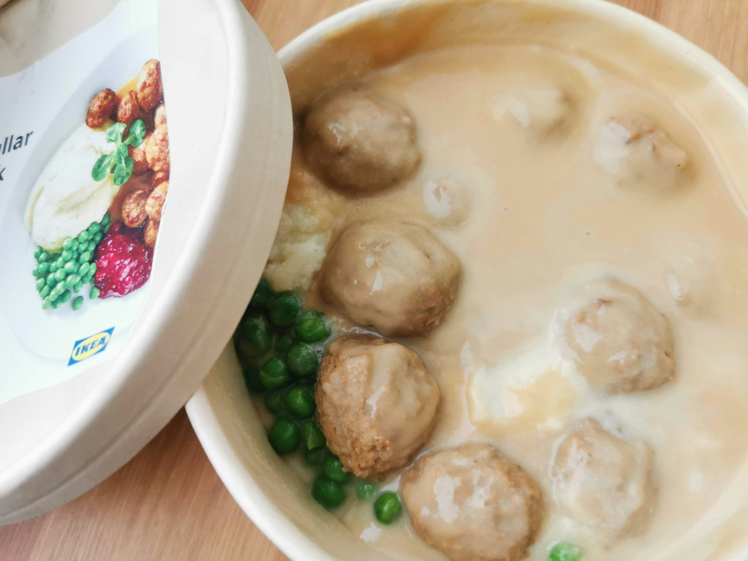 Un plat avec des boulettes de viande dans une sauce crémeuse avec des petits pois