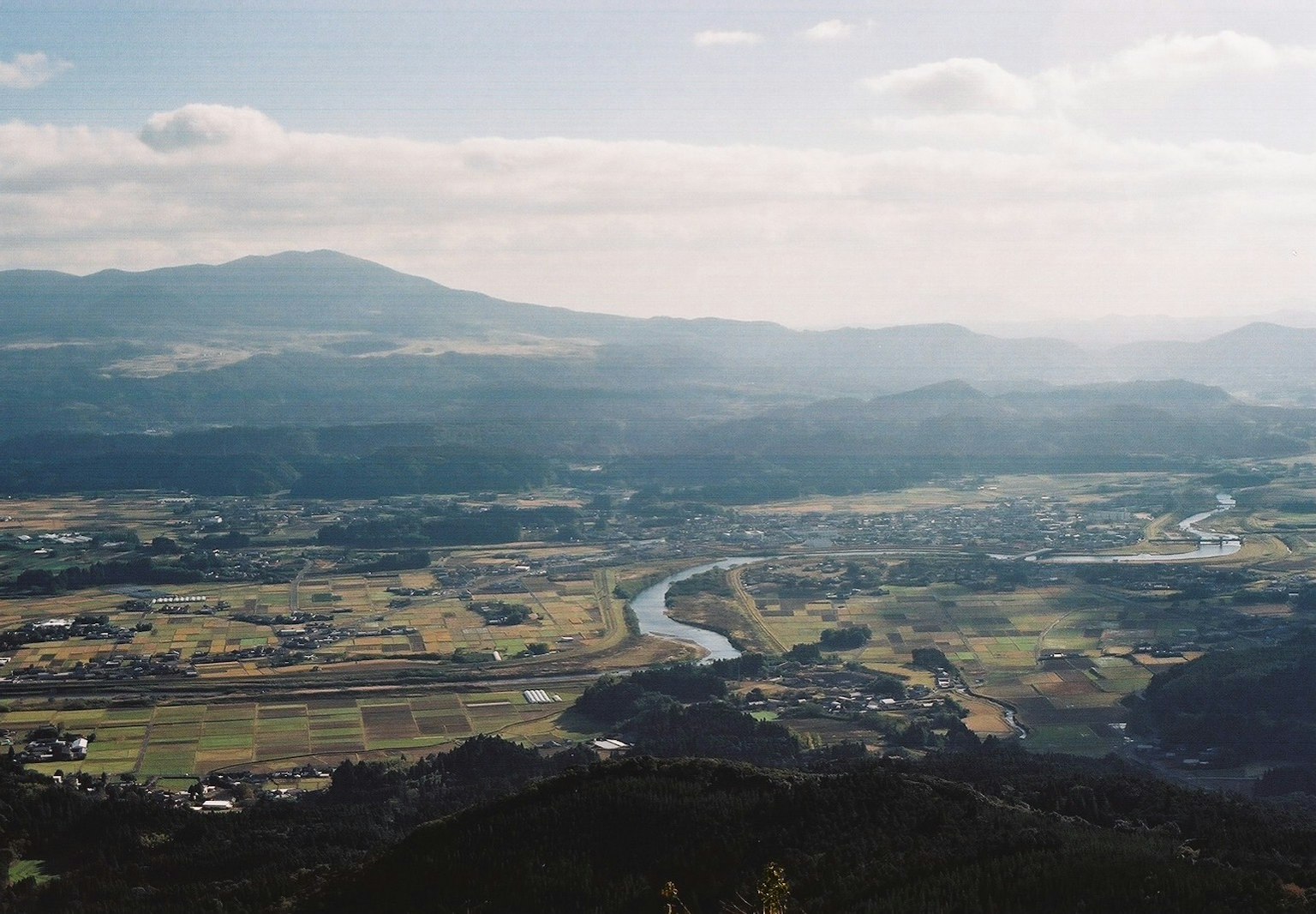 Panoramablick von einem Berg auf Ackerland und einen Fluss