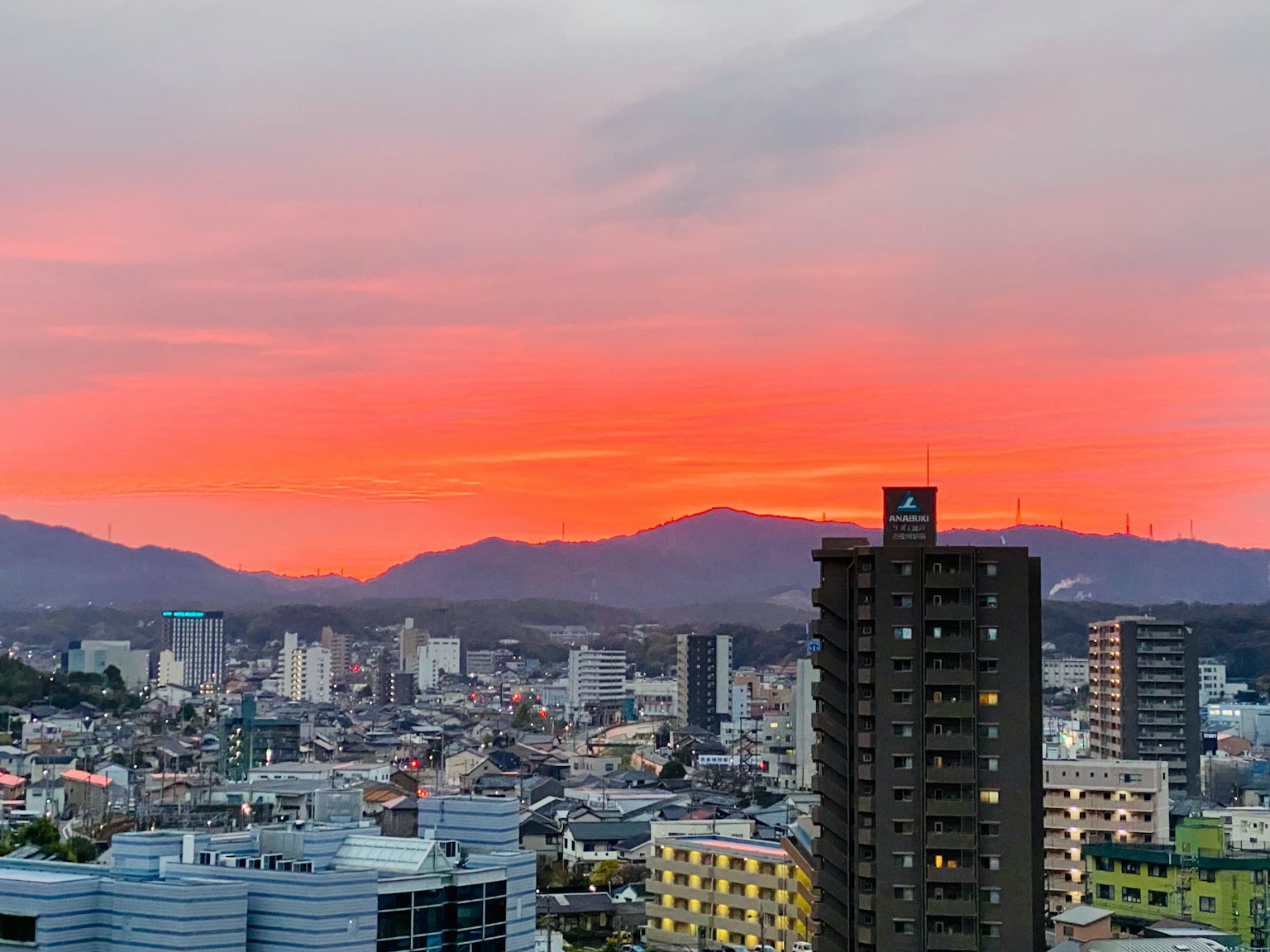Paysage urbain au coucher du soleil avec un ciel orange et rose vibrant montagnes en arrière-plan