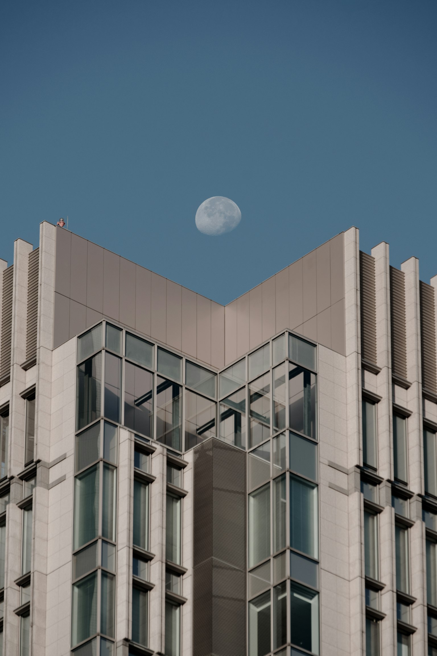 Edificio moderno con una luna prominente in un cielo blu chiaro