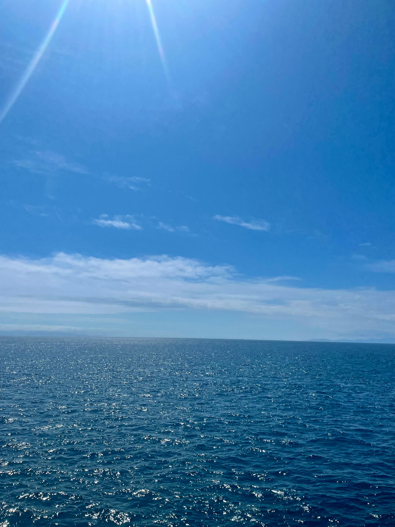 Vast blue ocean under a clear sky with shimmering water