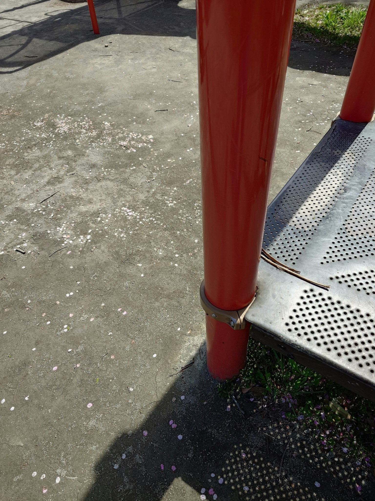 Parte di una struttura di gioco con un palo rosso e gradini in metallo