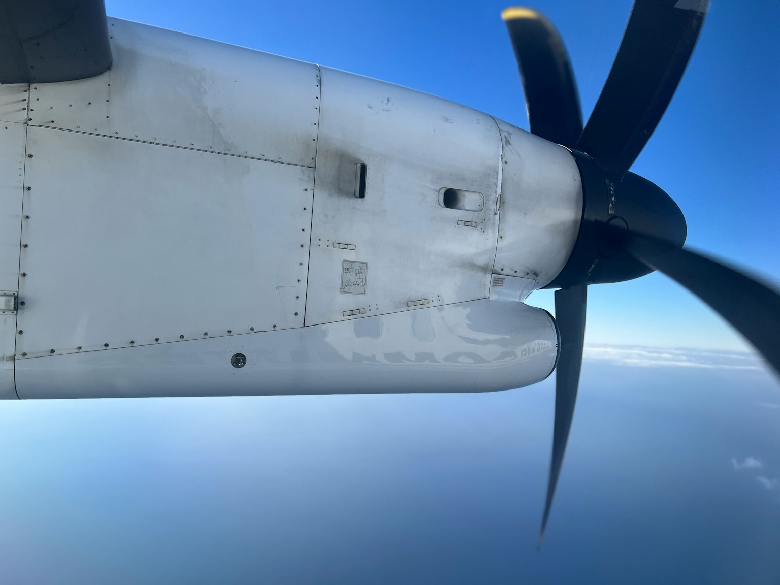 Image of an airplane propeller and wing against a blue sky