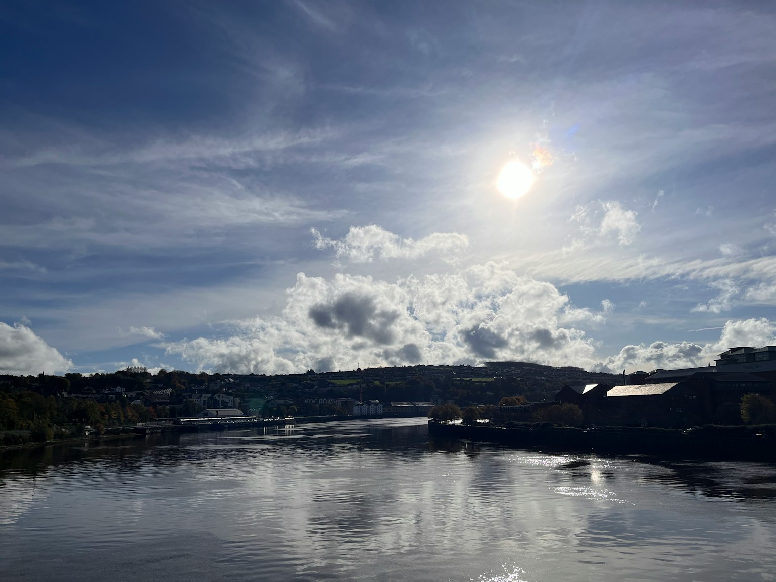 Paisaje con un río y cielo con el sol y nubes
