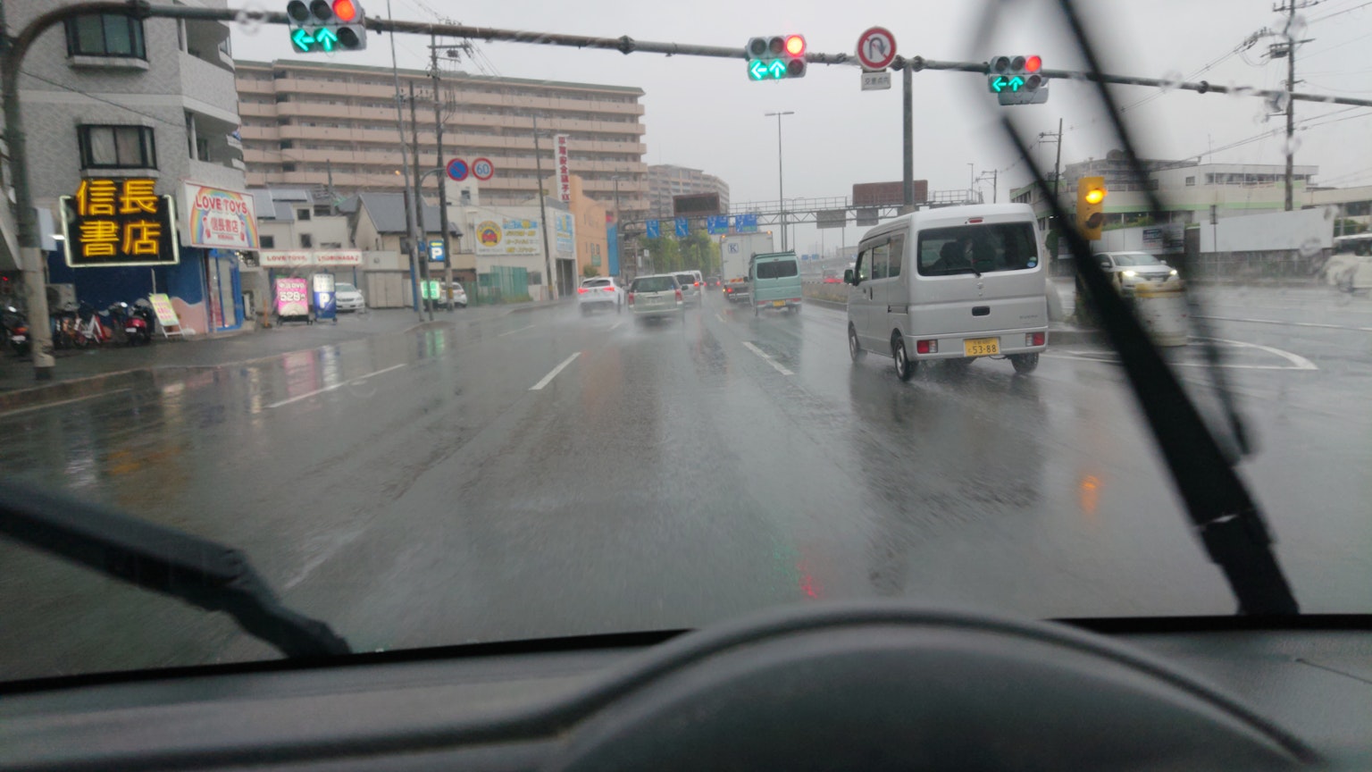 View of an intersection in the rain from inside a car