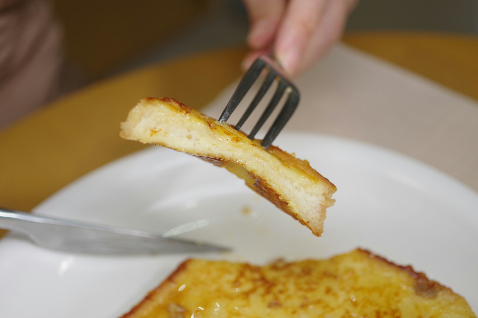 Una fetta di toast sollevata con una forchetta sopra un piatto con un coltello