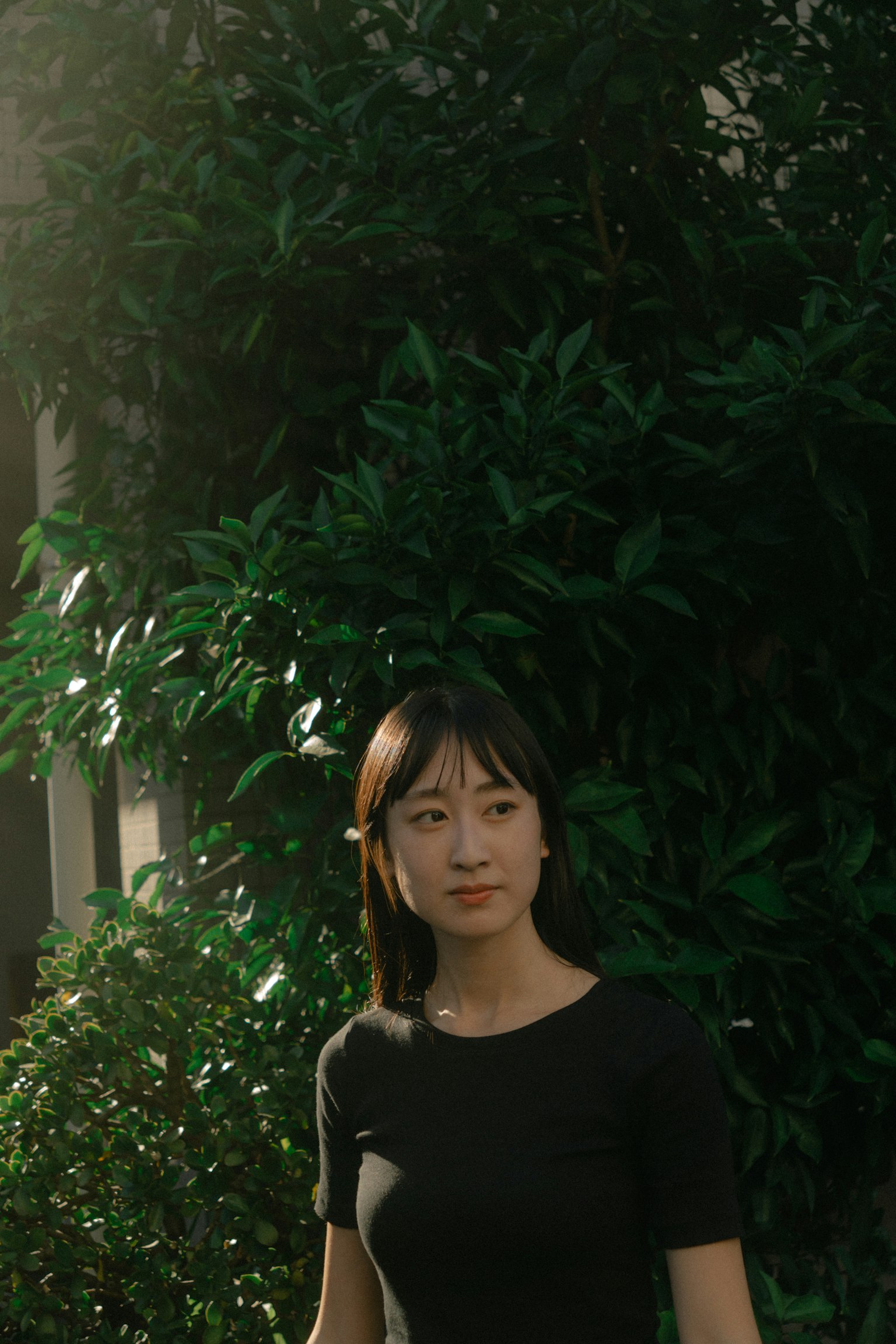 Portrait of a woman standing in front of lush green foliage