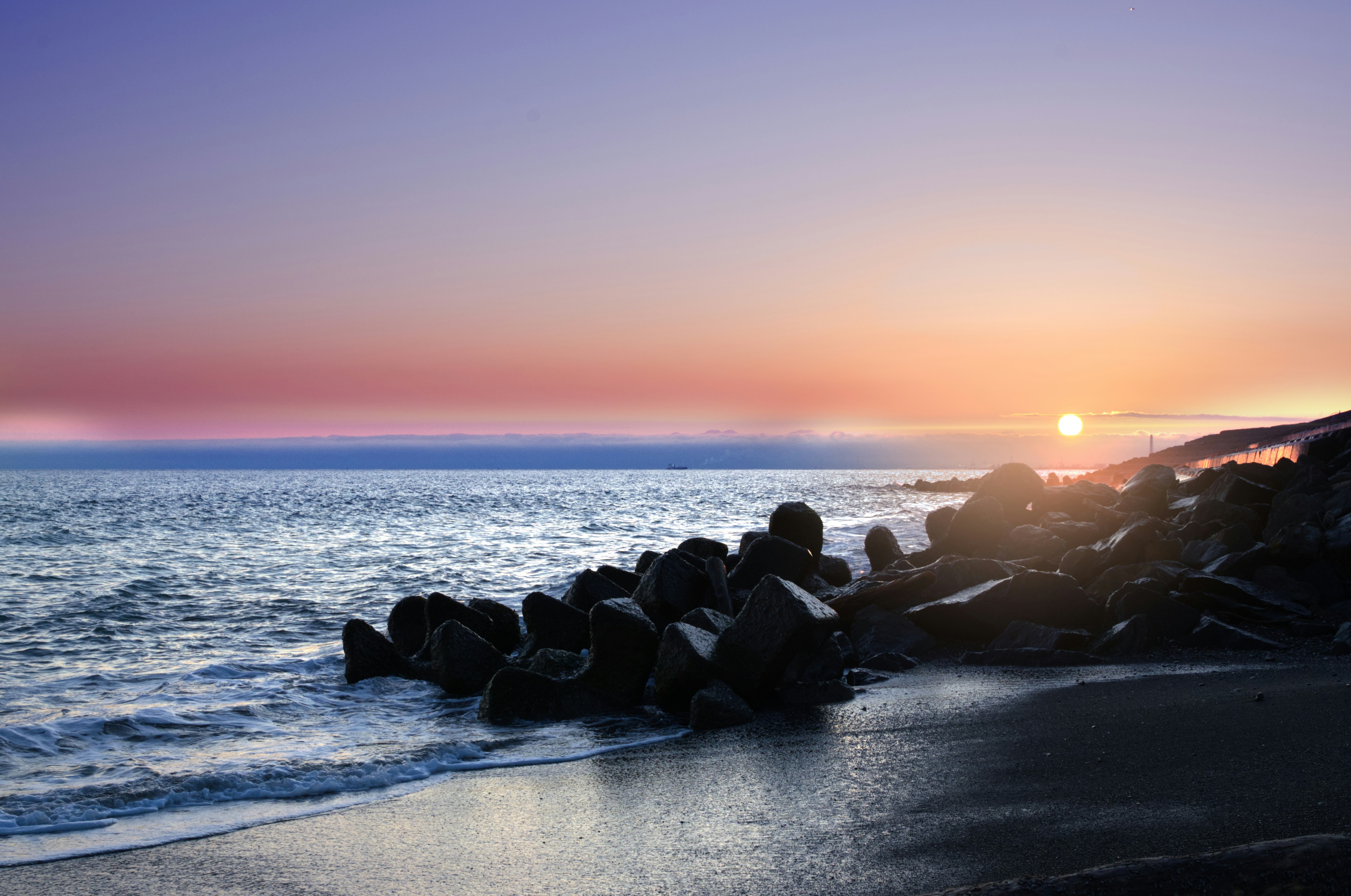 防波堤の石積みと夕焼けの海岸線