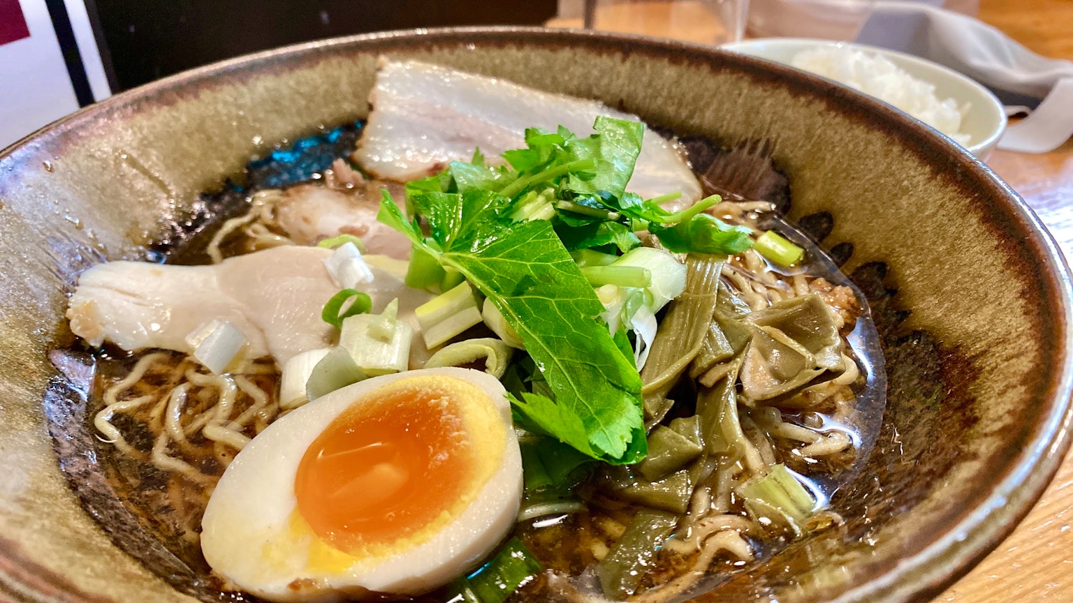 Ciotola di ramen con fette di maiale, uovo a cottura lenta, cipolle verdi e verdure