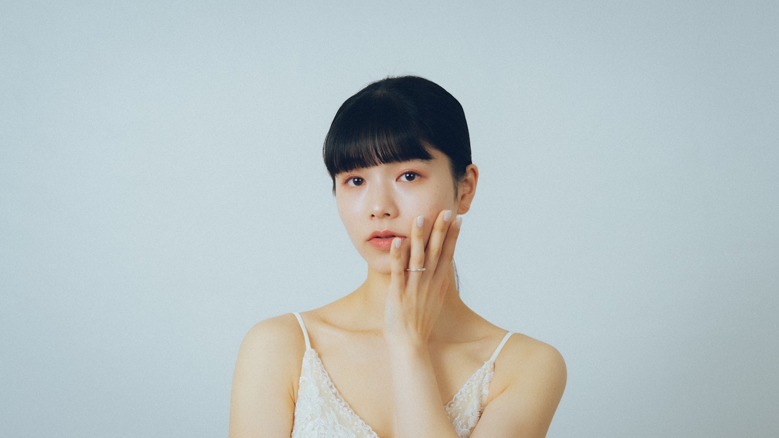 一位女性在中性背景前触摸她的脸