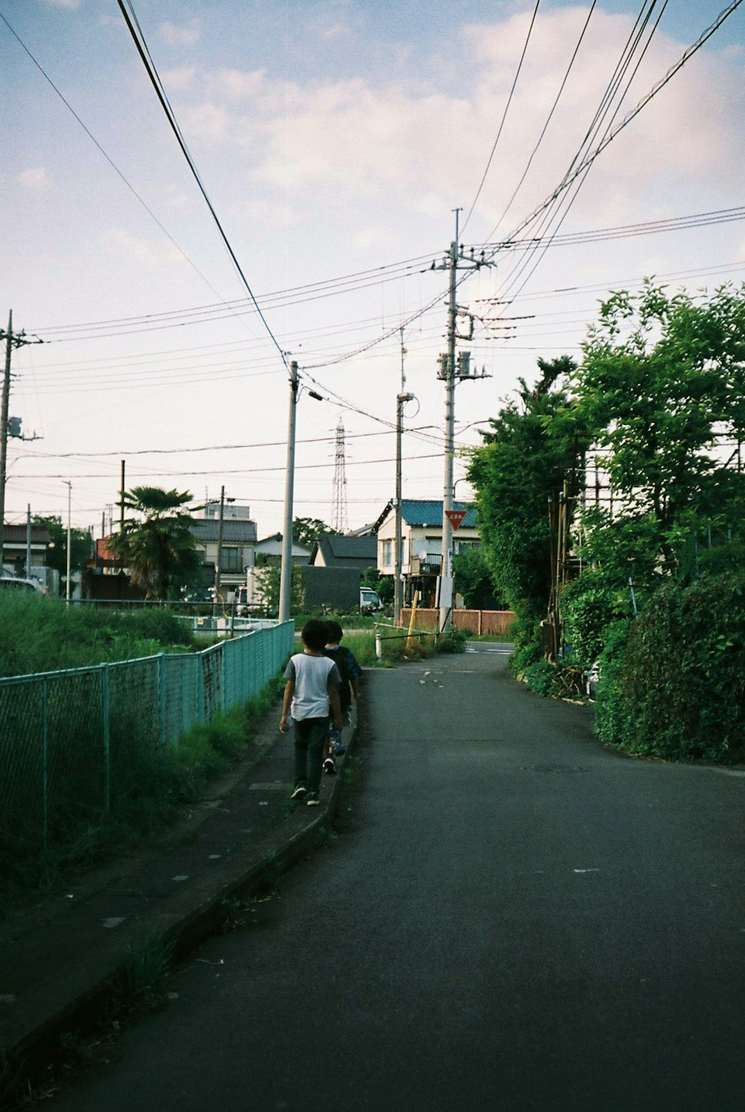 A person walking through a quiet residential street with power lines