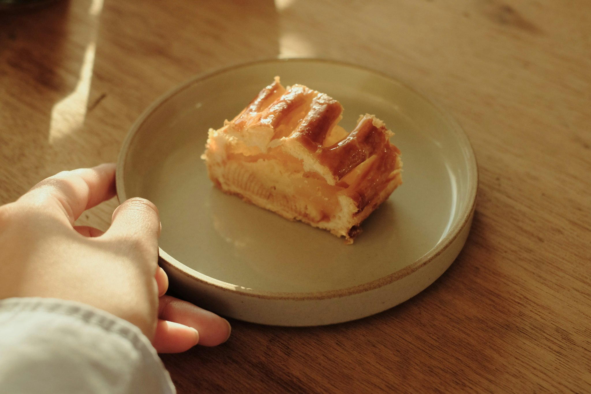 una mano che tiene un piatto con una torta di mele