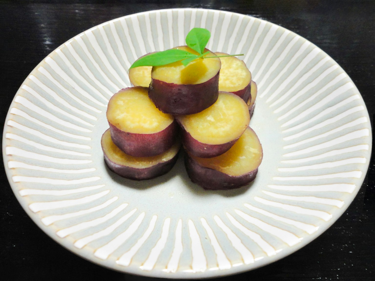 Rodajas de batata dispuestas en un plato decorativo con una hoja verde