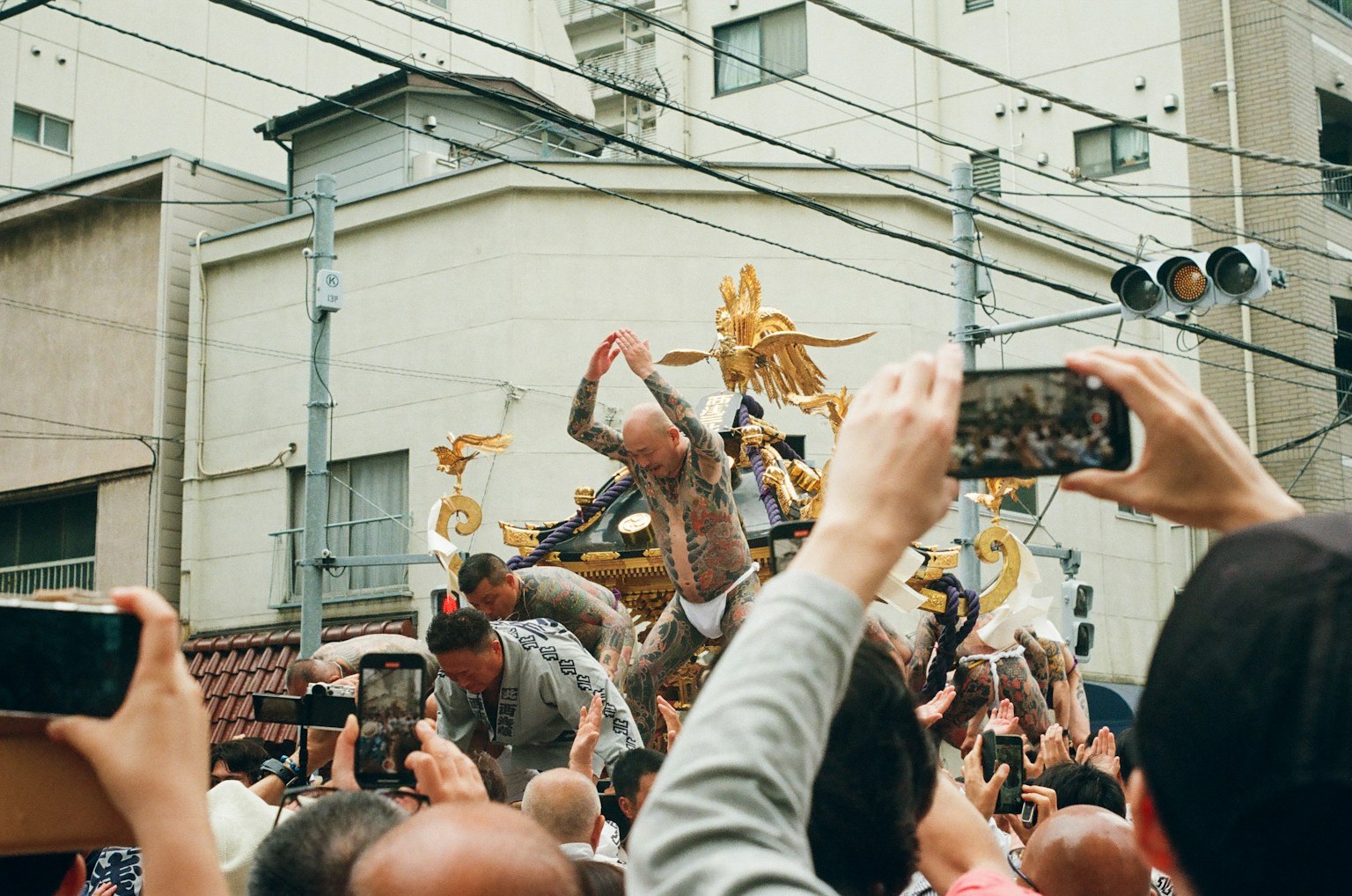 参与者在节日中抬着一个便携式神社周围的人们正在用智能手机拍照