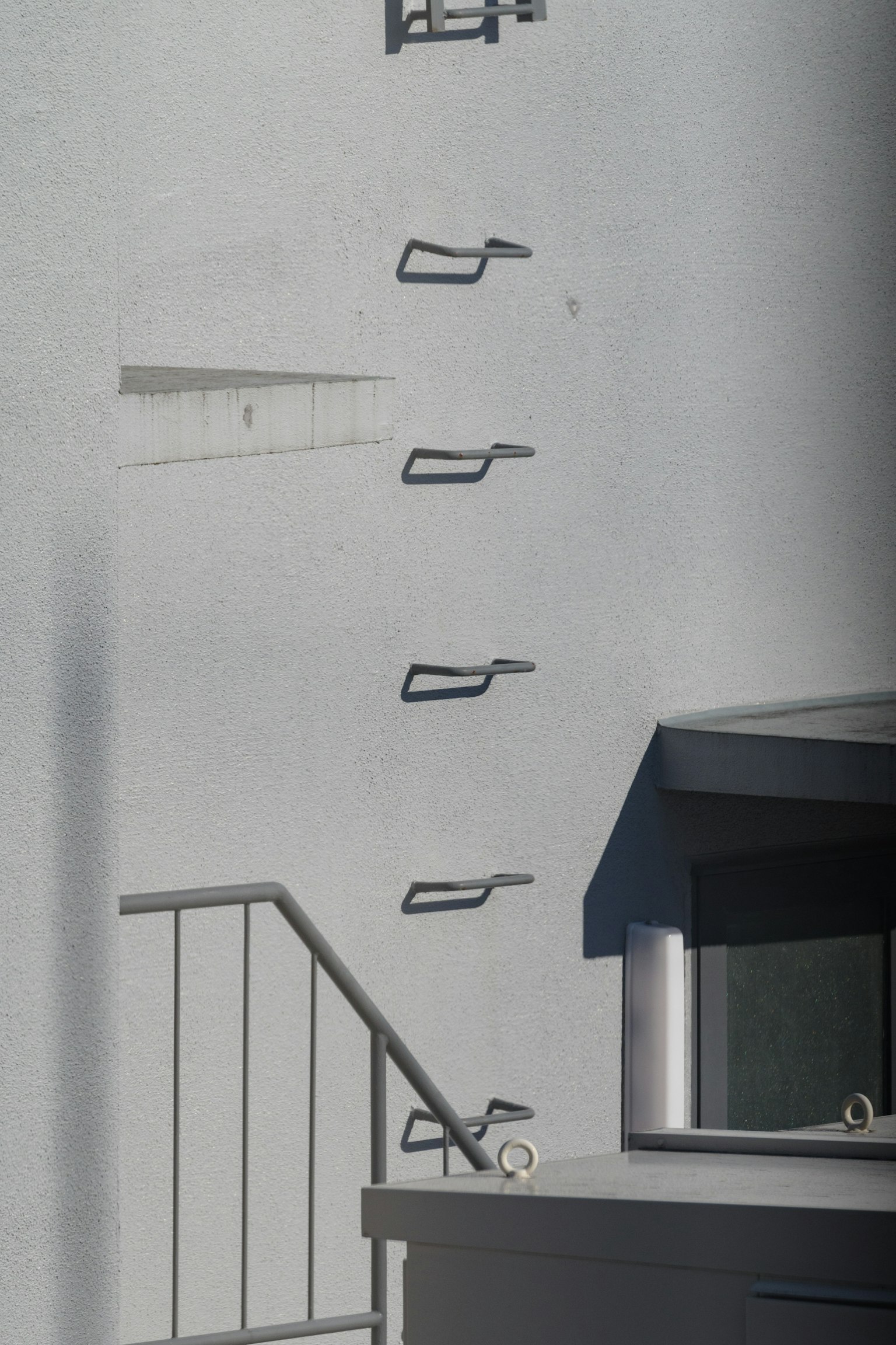 Metal handrails mounted on a white wall with a staircase visible