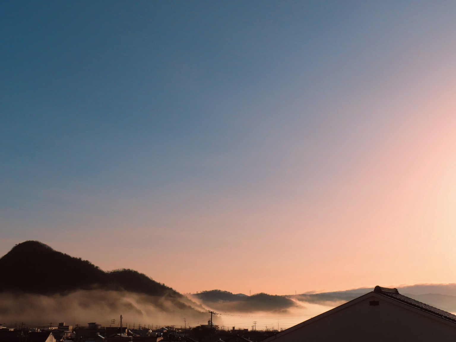 朝焼けの空と山々の風景に霧が漂う
