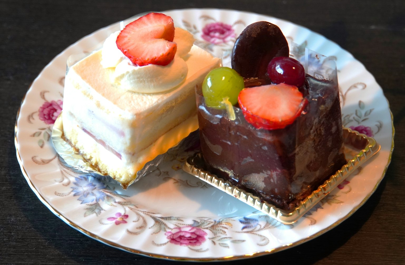 Un bel piatto con una torta bianca e una torta al cioccolato guarnita con frutti