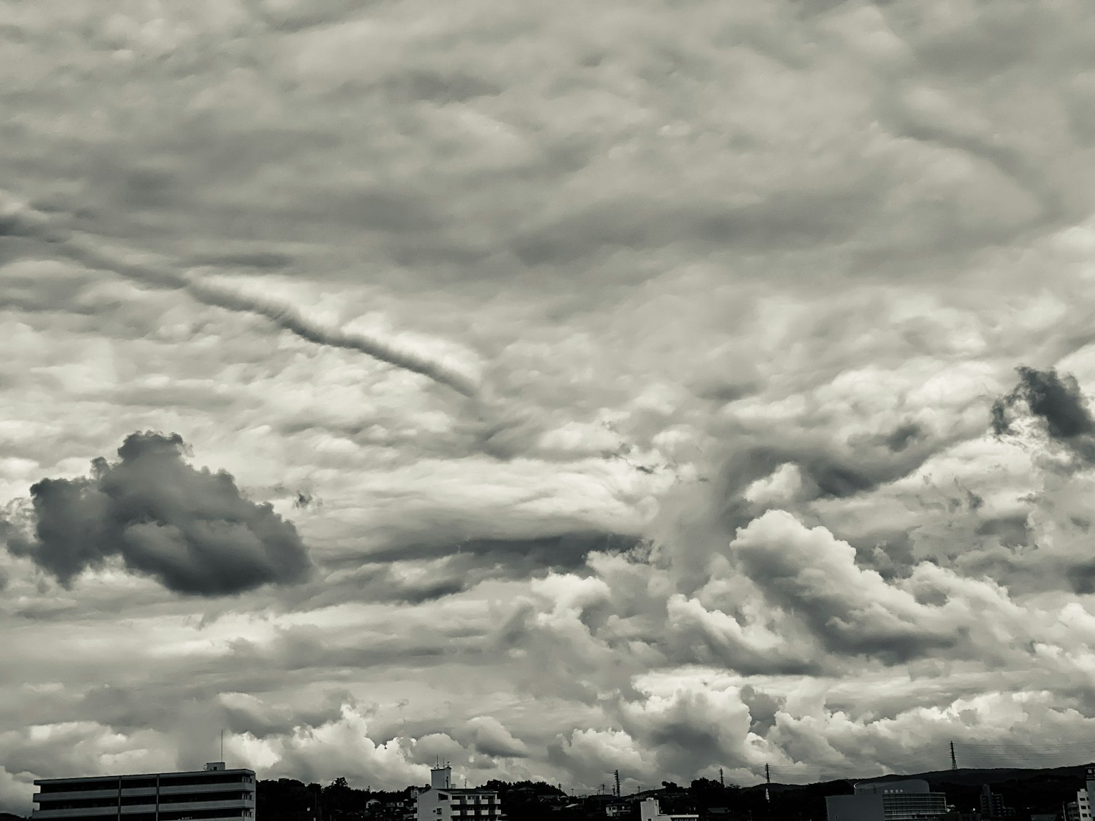 Langit abu-abu dipenuhi awan dan siluet bangunan