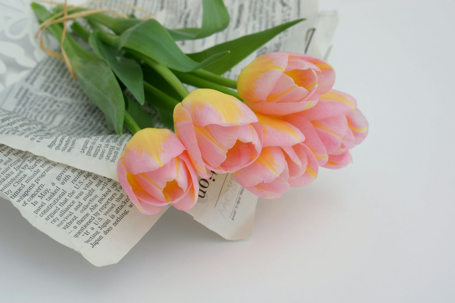 Một bó hoa tulip hồng nhạt đặt trên báo
