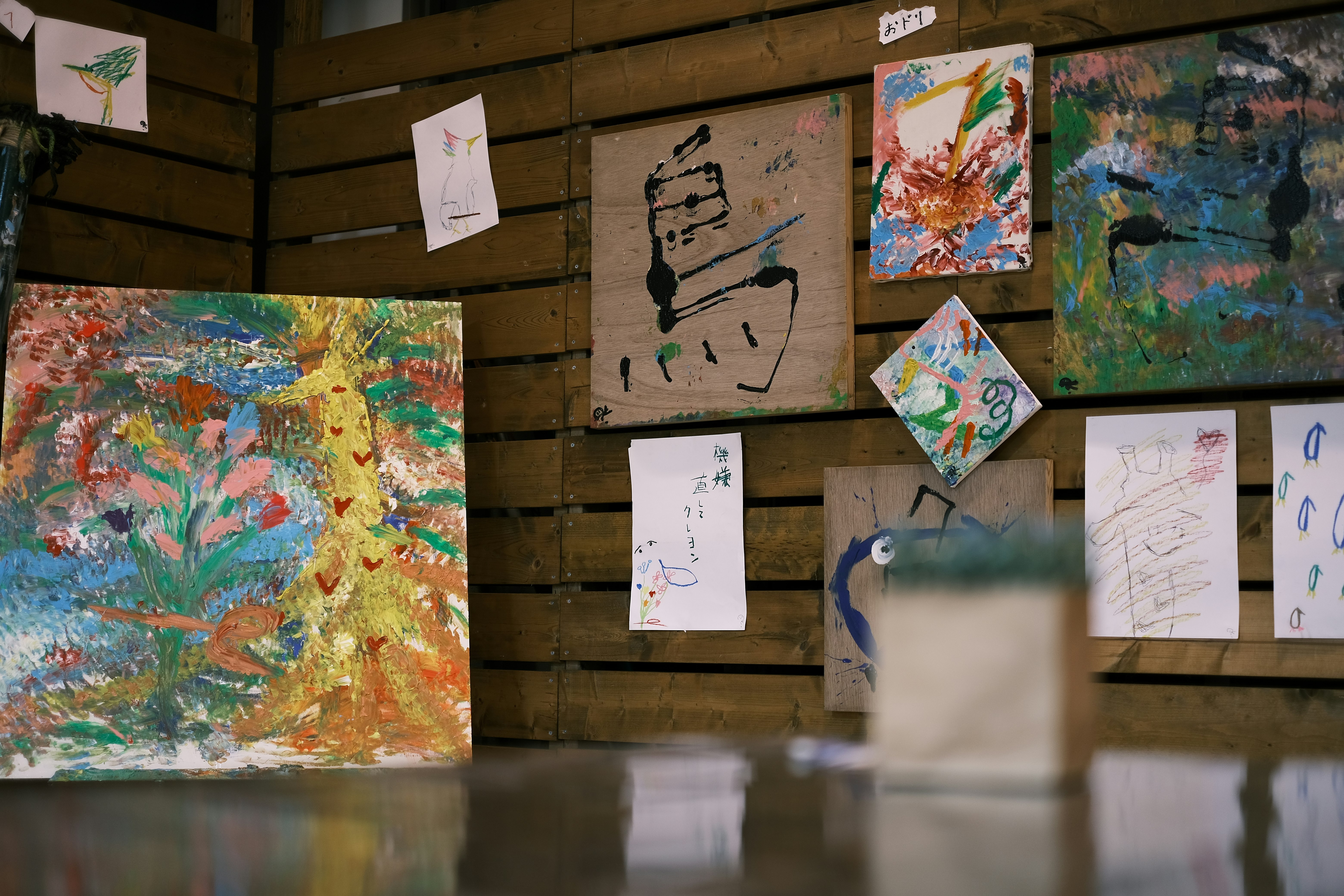 木製の壁に飾られた絵画や紙の作品