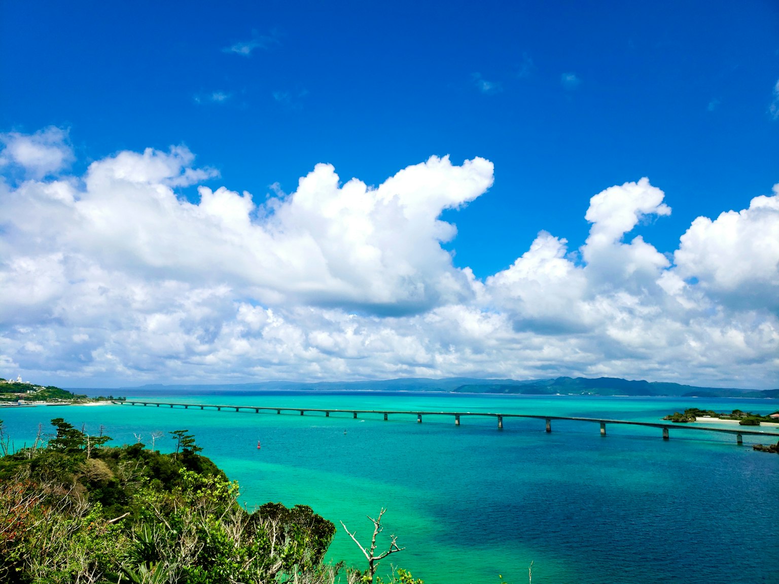 ทิวทัศน์ของมหาสมุทรสีน้ำเงินและเมฆสีขาวพร้อมสะพานข้ามน้ำ