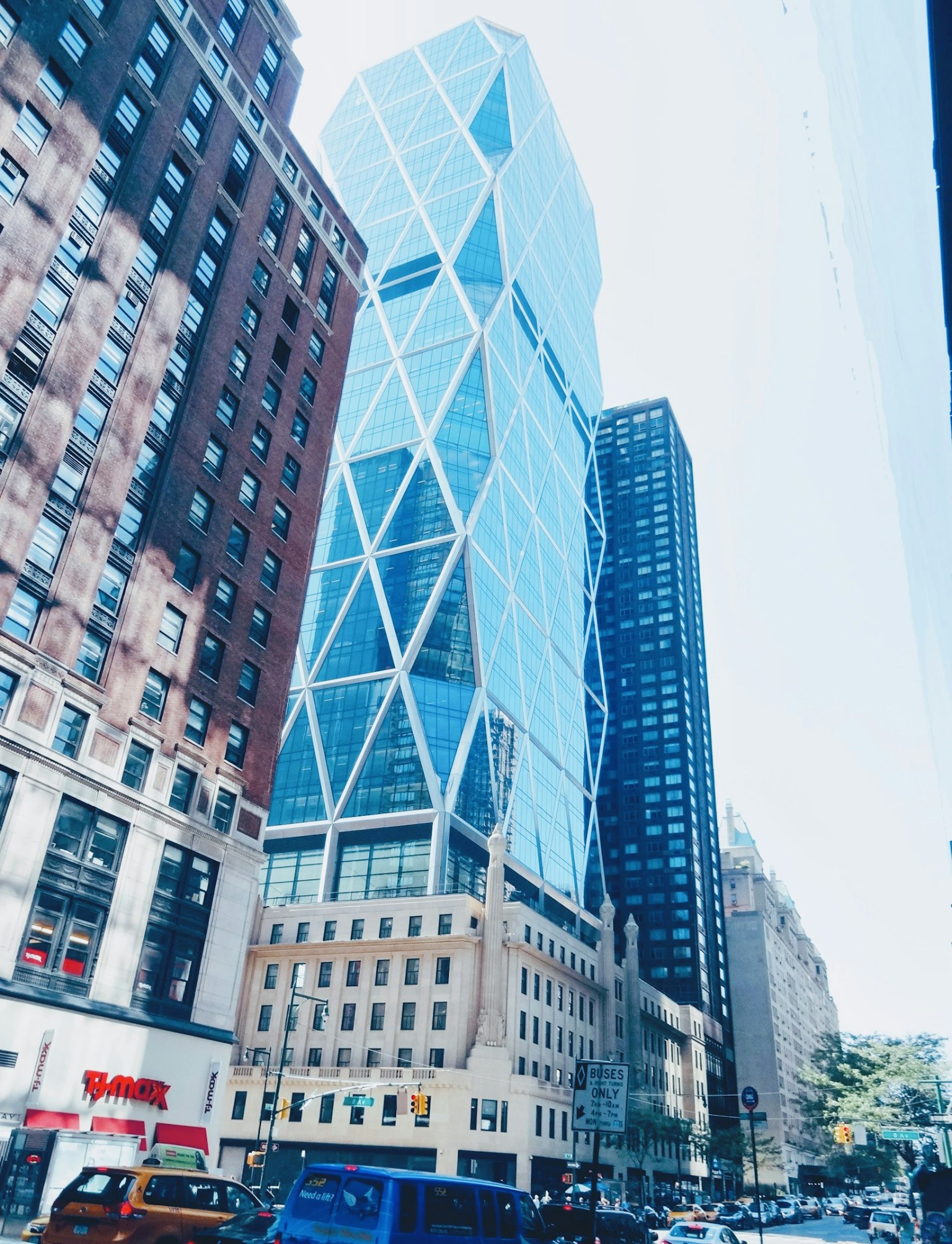 Modern skyscraper with blue glass facade standing between older buildings