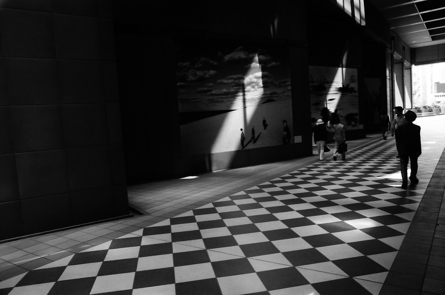 Escena urbana en blanco y negro con sombras en una acera a cuadros