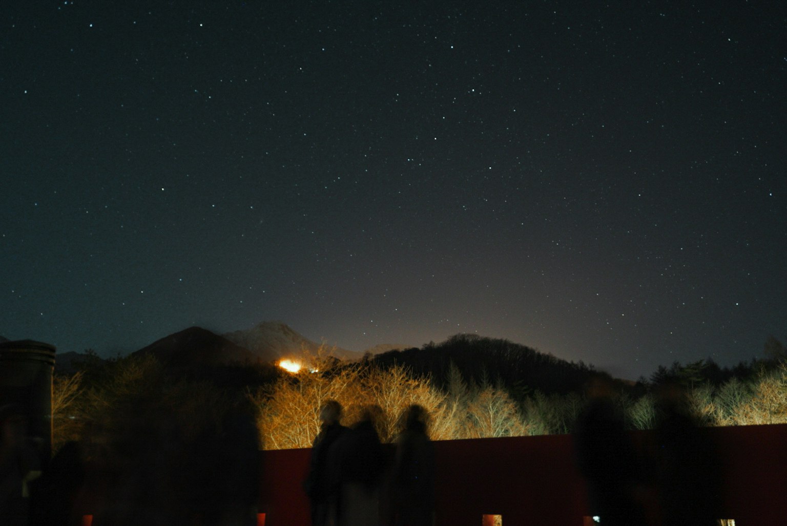 星空下的山脉夜景，远处有光点